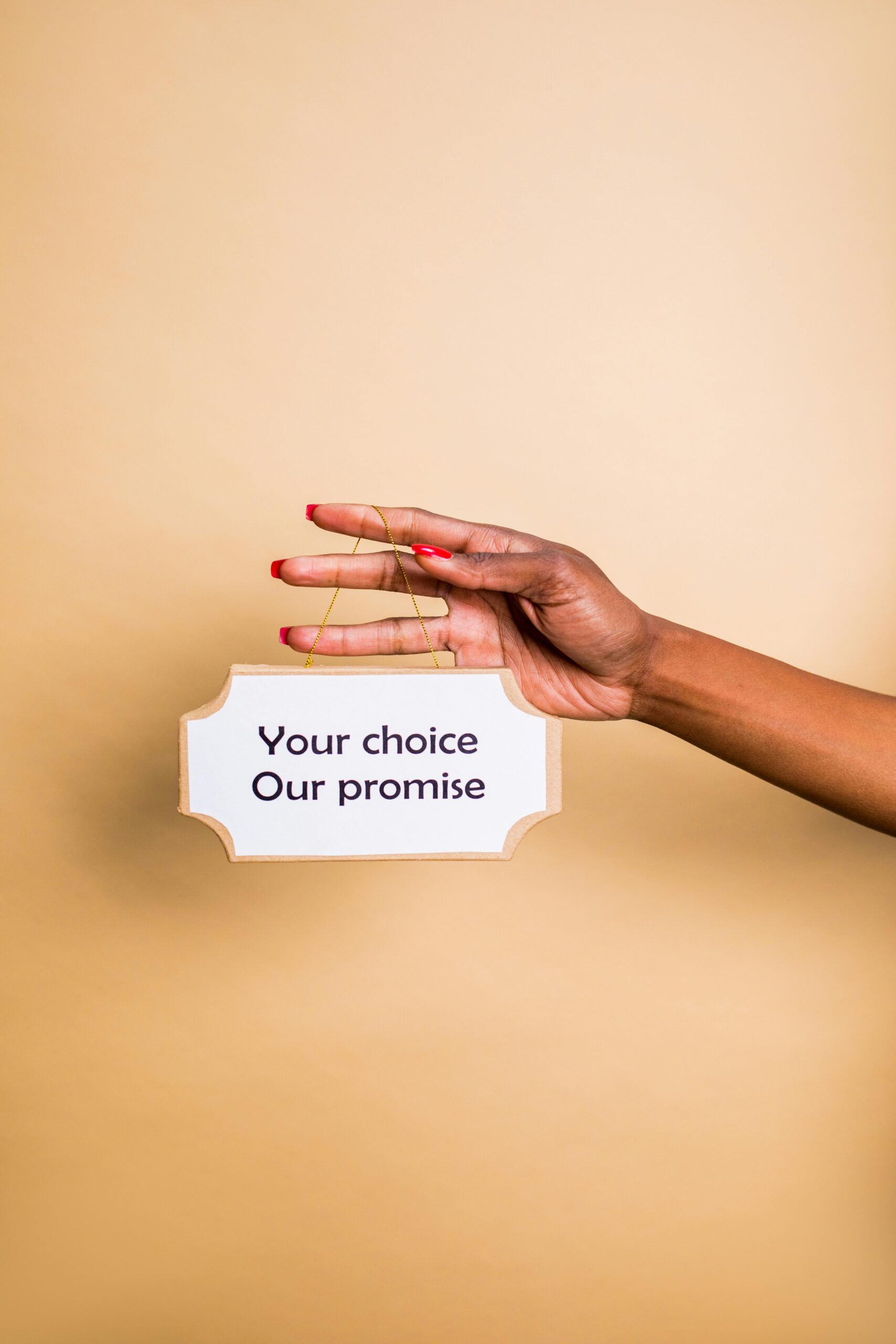 A hand holding a sign with the message 'Your choice, Our promise' on a neutral background.